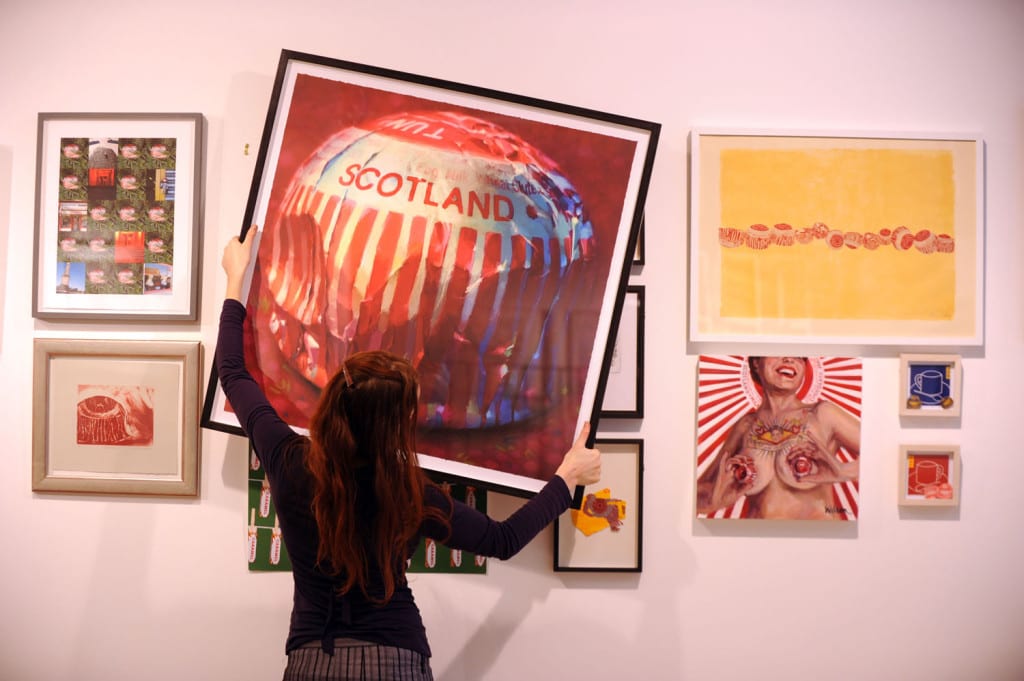 Tunnocks exhibition at the Glasgow Print Studio. Assistant Olivia Bliss moves the artworks around. . Picture: Robert Perry 
