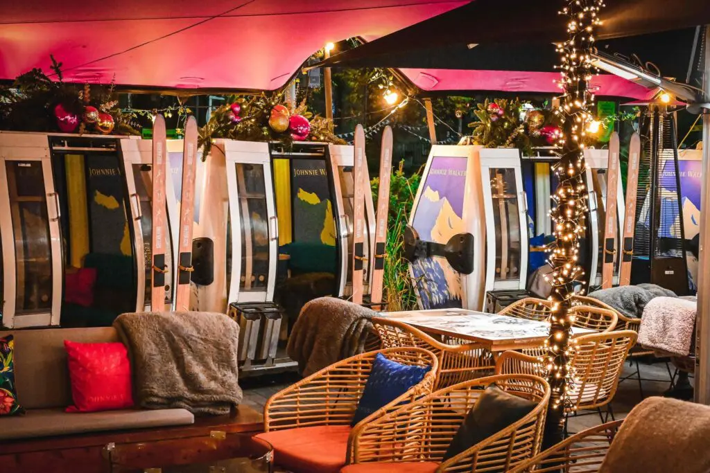 The terrace at McLarens on the Corner at night, with fairy lights lighting the seating area outside the ski gondolas. 