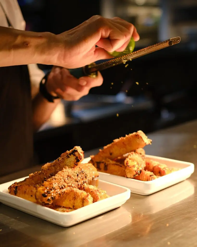 A chef garnishing two Ka Pao dishes with lime. 