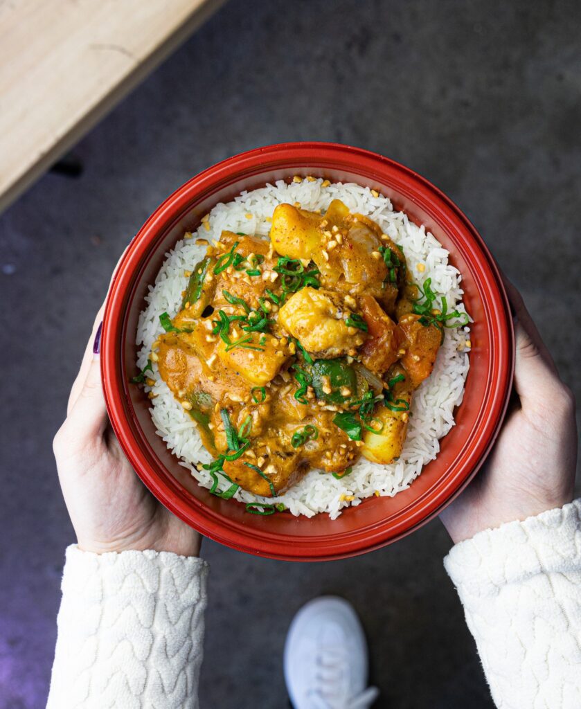 Someone holding a bowl of curry from Thai Express Kitchen. 